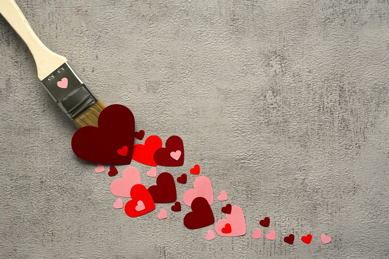 A paint brush leaving a trail of red and pink hearts representing love people feel about becoming a parent