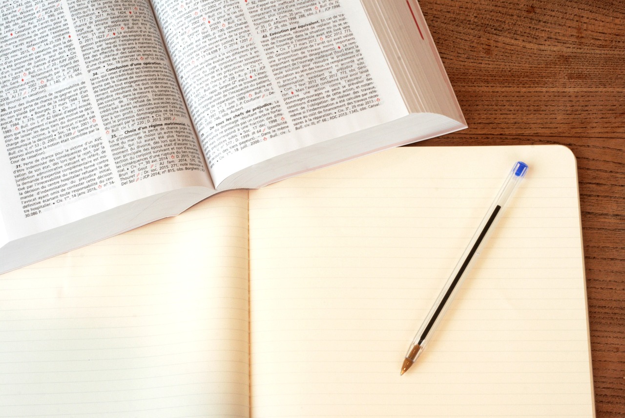An open text book resting on a notepad and pen symbolising research about a birth parent opposing an adoption application