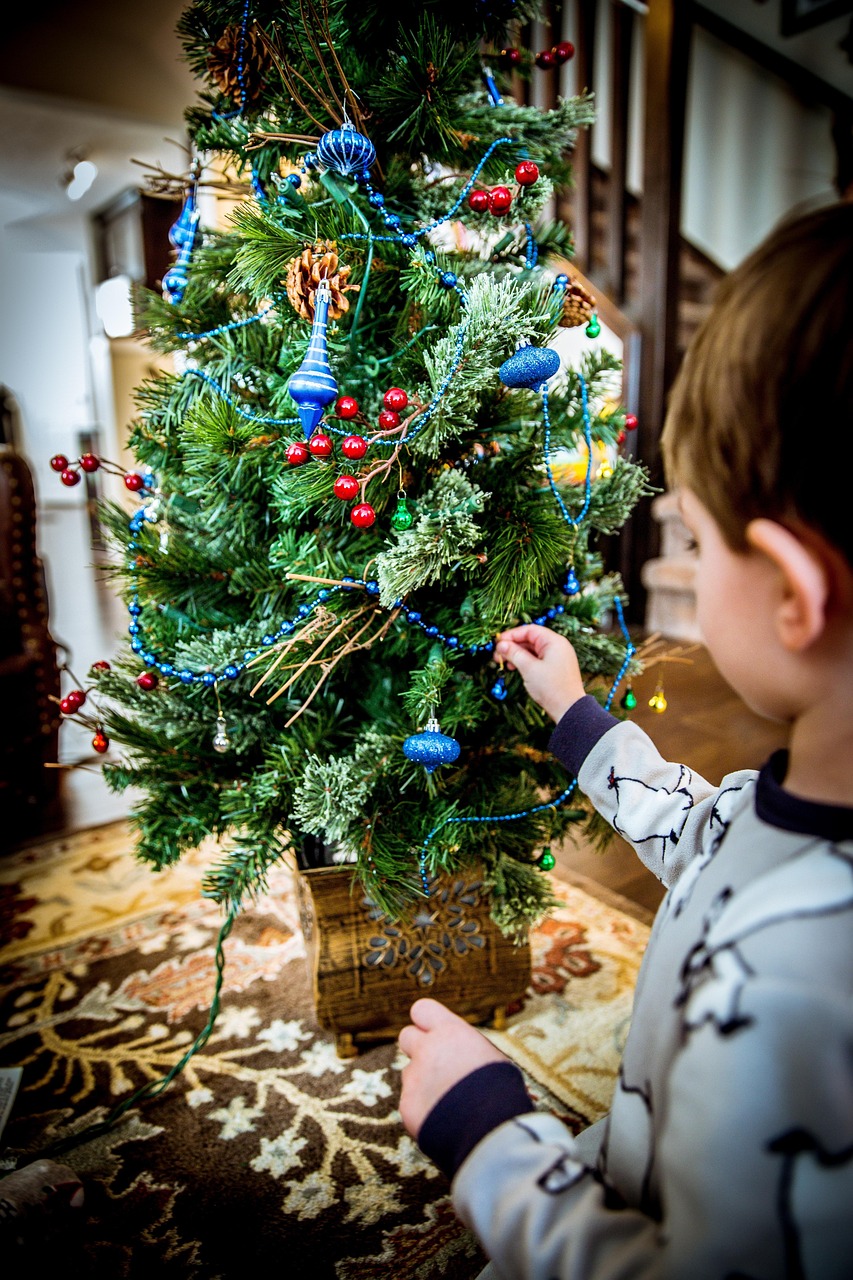 A child decorating a small Christmas tree representing how to help children navigate the festive season