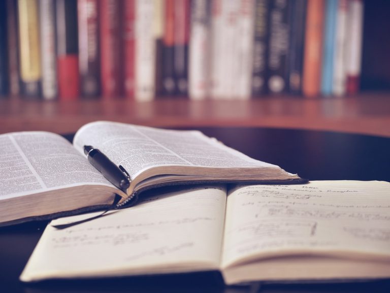 An open legal textbook and an open legal notepad with books on a shelf in the background