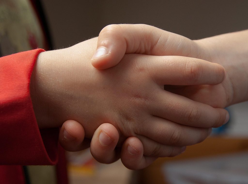Two children's hands shaking each other representing adoption in the US in 2026