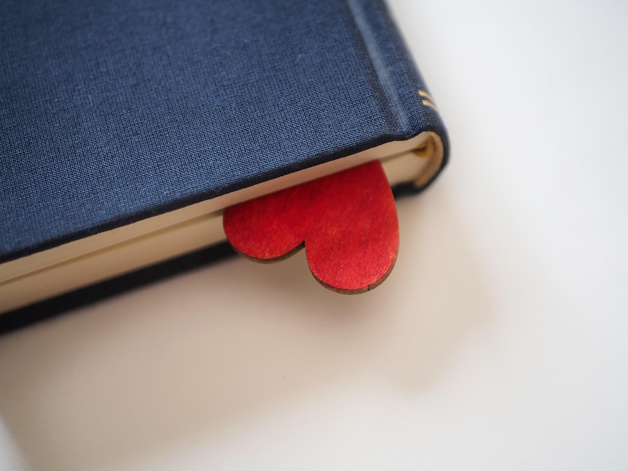 A red wooden heart sticking out of a blue hard-backed book