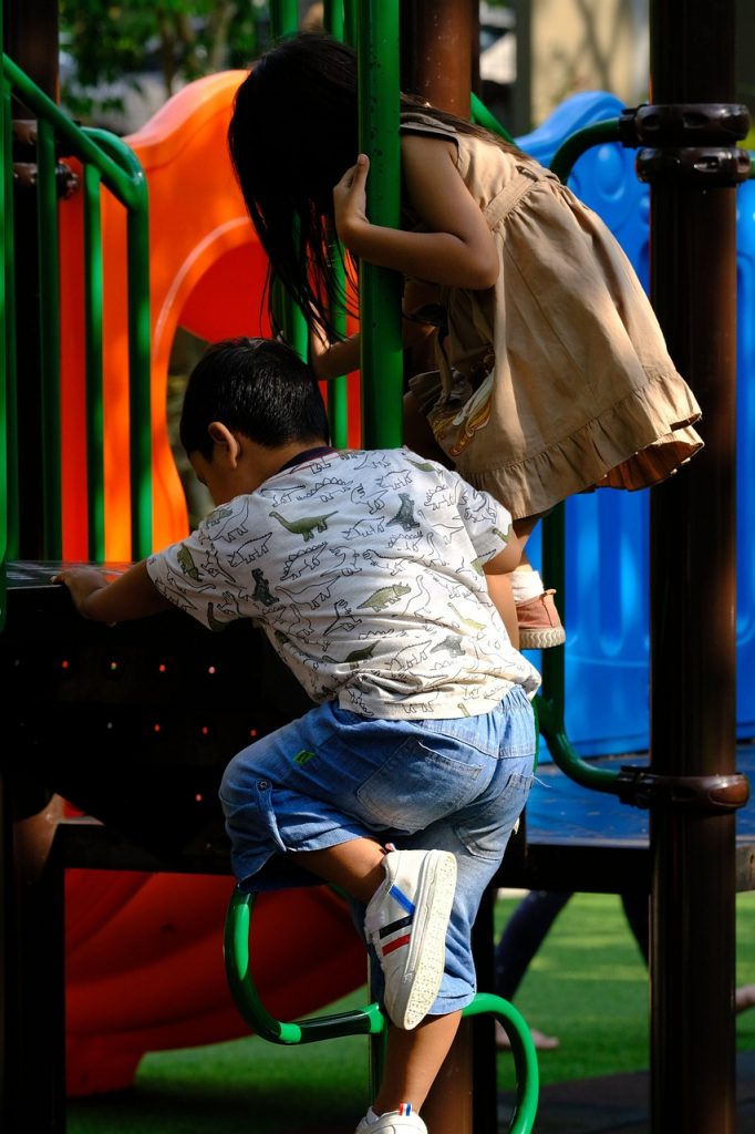 A girl and boy playing on a on play equipment
