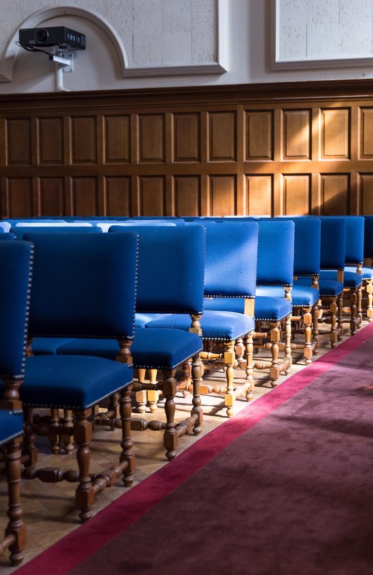 A row of blue chairs in a courtroom representing someone applying to adopt without the LA’s support