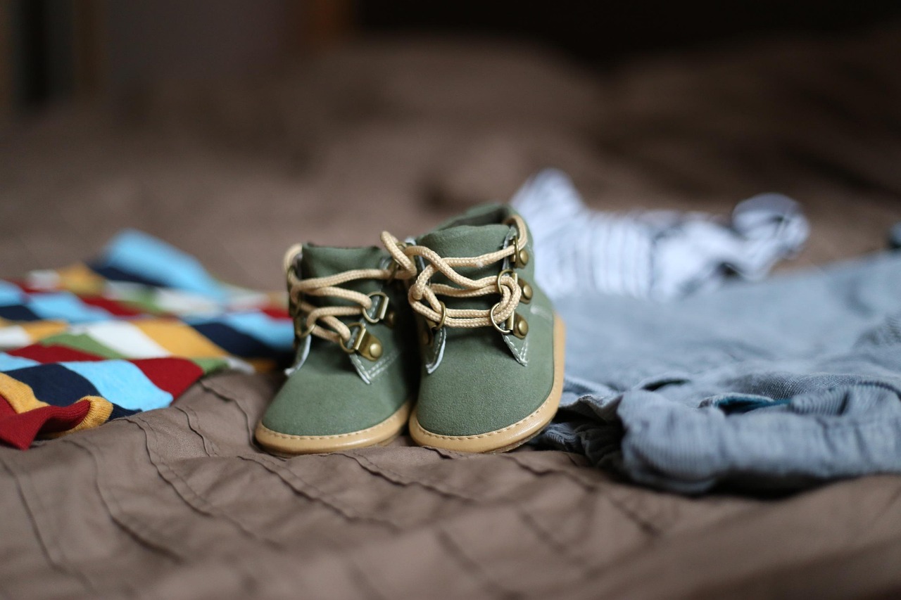 A pair of green baby boots resting on folded up clothing