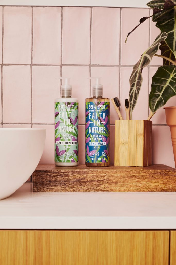 Faith in Nature Lavender and Geranium products on a wooden shelf next to a wash basin