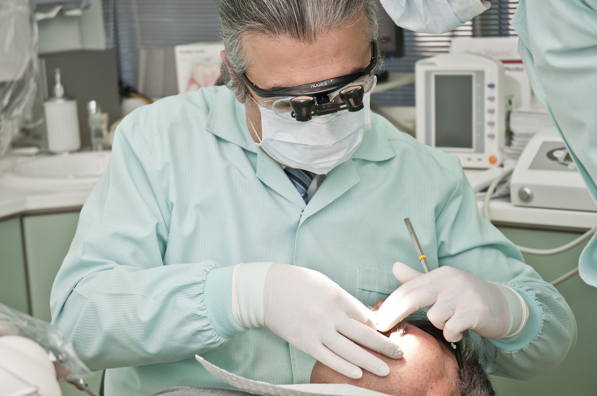 A dentist wearing PPE looking into a patient's mouth