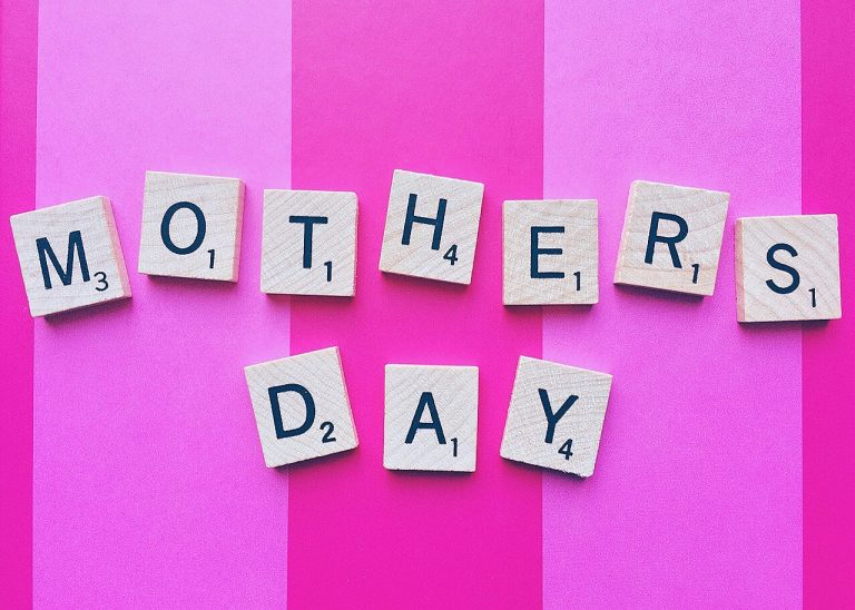 Scrabble tiles spelling Mother's Day against a pink striped background