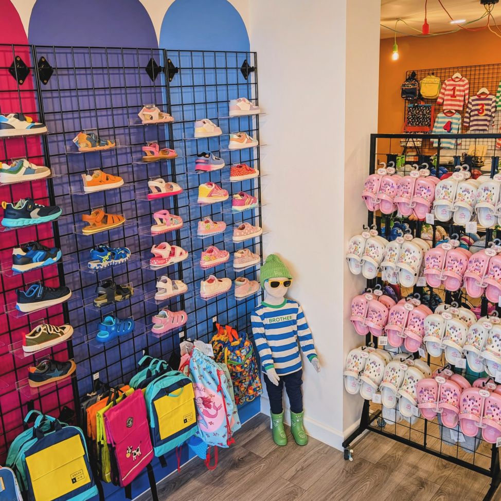 The inside of a shoe shop with shelves of shoes and a mannequin of a child