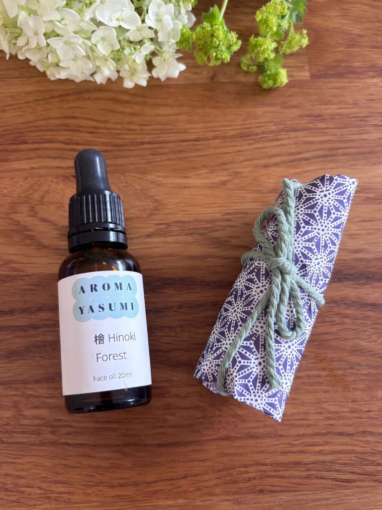 Image of Hinoki - Forest Face and Beard Oil bottle next to a fabric gift wrap and white flowers