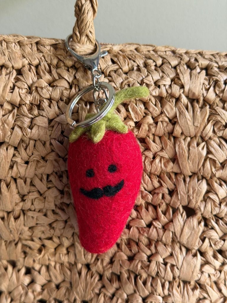 Mr Chilli Bag charm hanging from a knitted bag handle