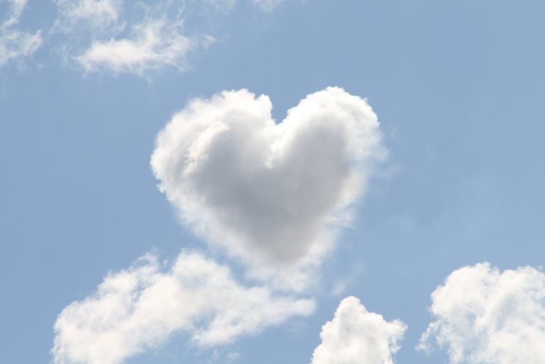 A white cloud shaped as a heart in a blue sky, representing love isn't born, it's built