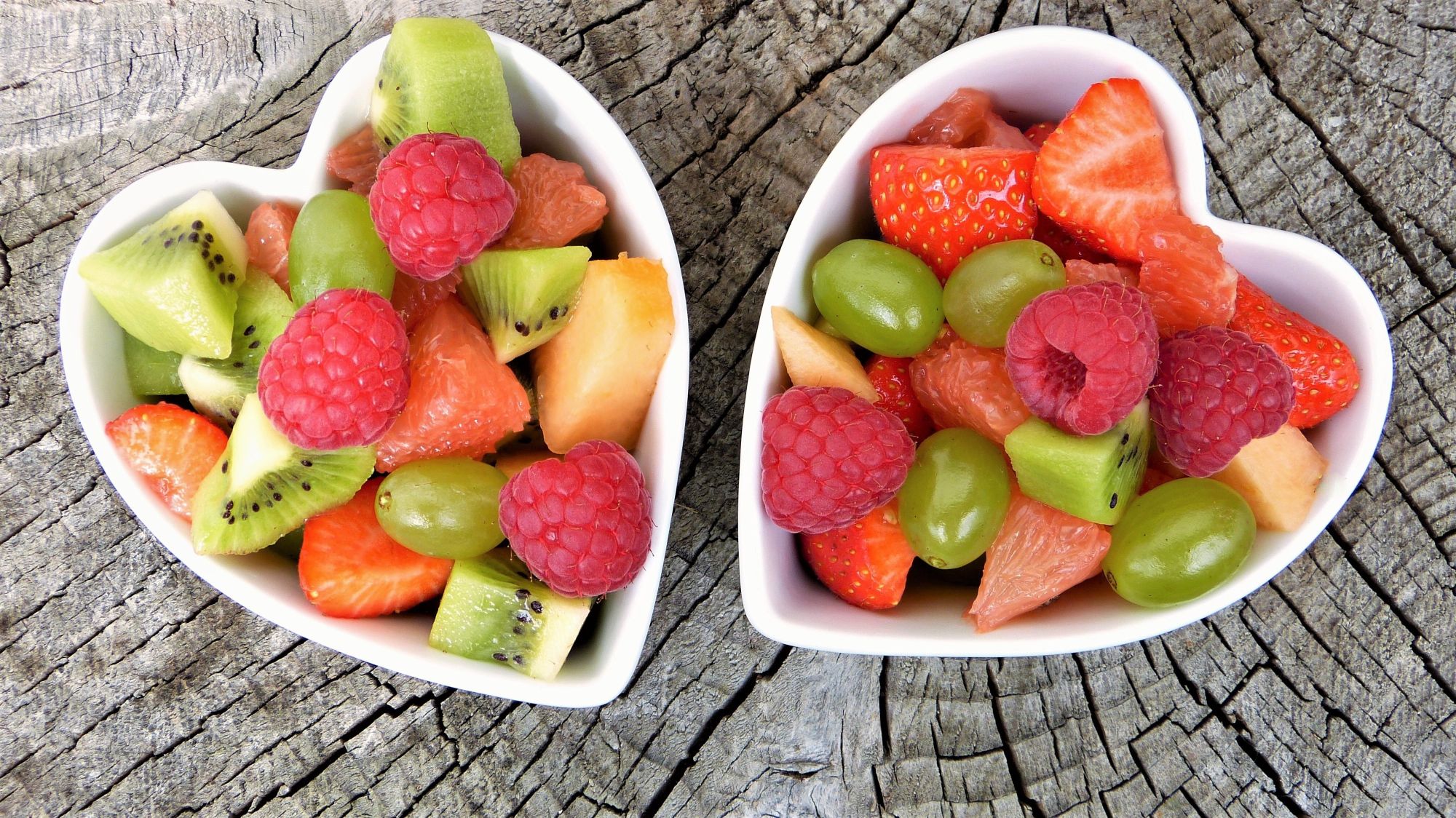Two heart=shaped bowls filled with fresh fruit