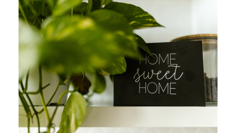 Home sweet home sign in the background with plant leaves in the foreground