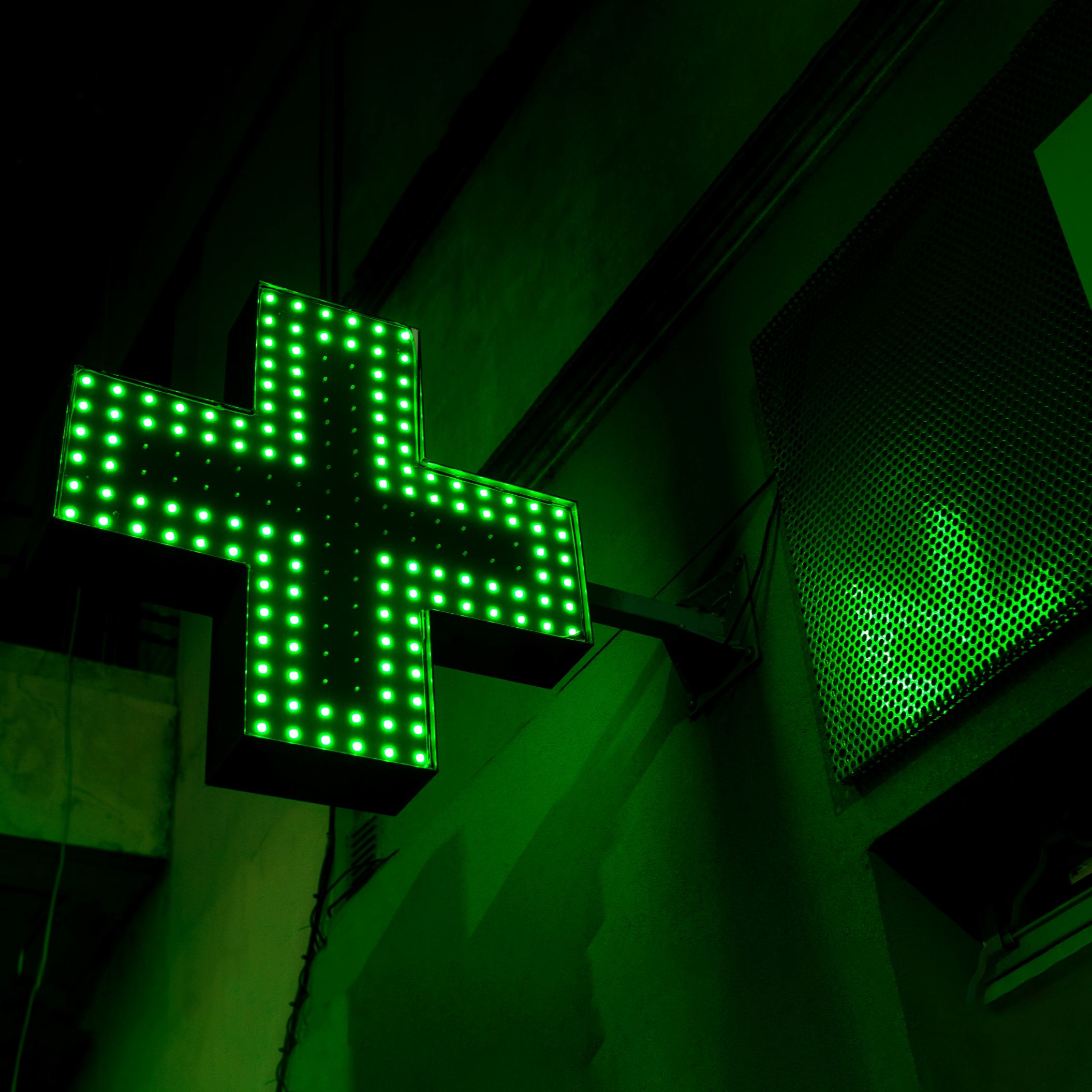 A green cross in lights against a black background